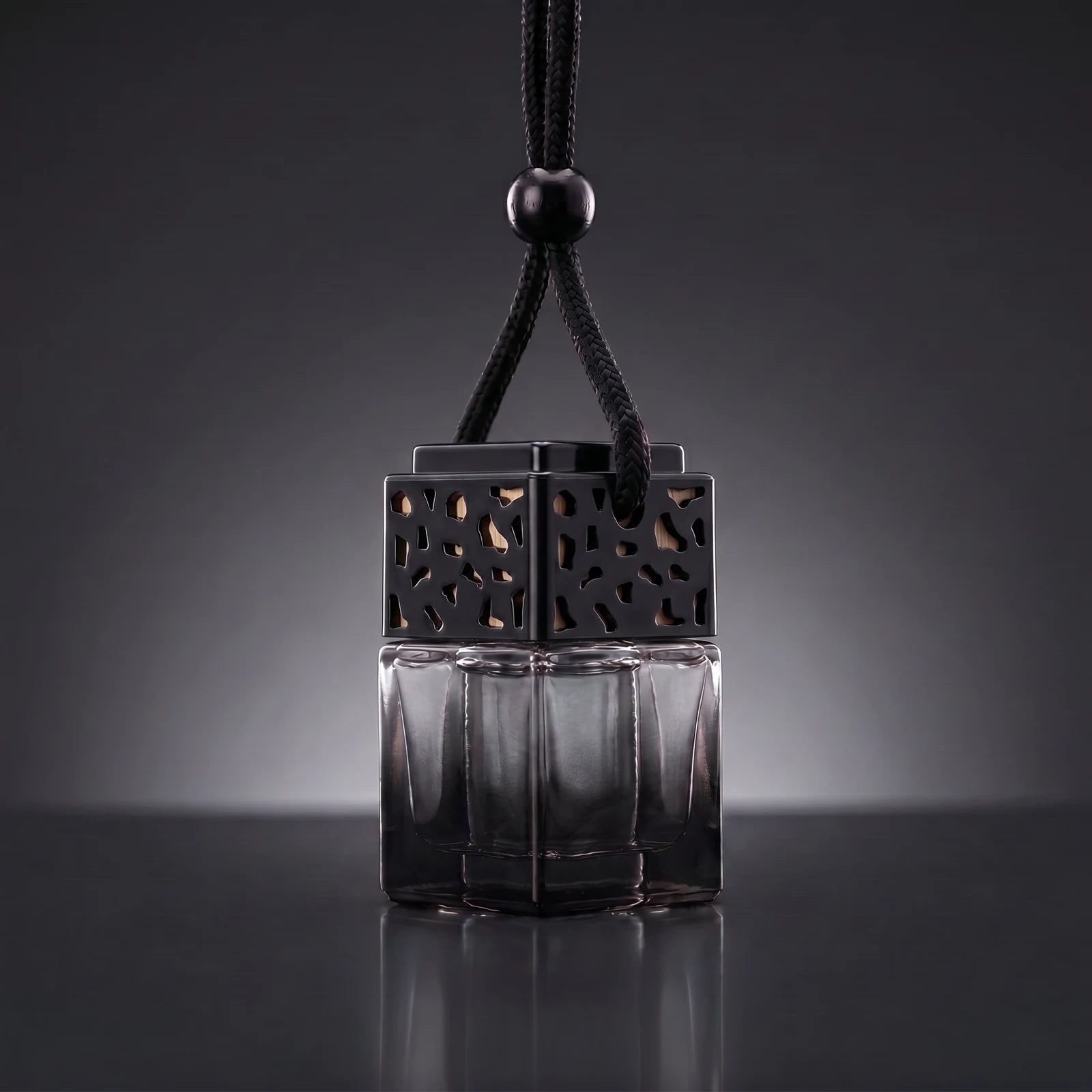 Black FRESURE car diffuser — smoky black glass cube bottle with black lattice cap on a dark studio background