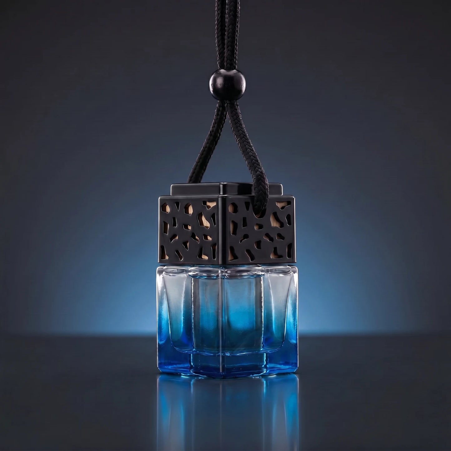 Blue FRESURE car diffuser — ocean blue tinted glass cube bottle with black lattice cap on a dark studio background