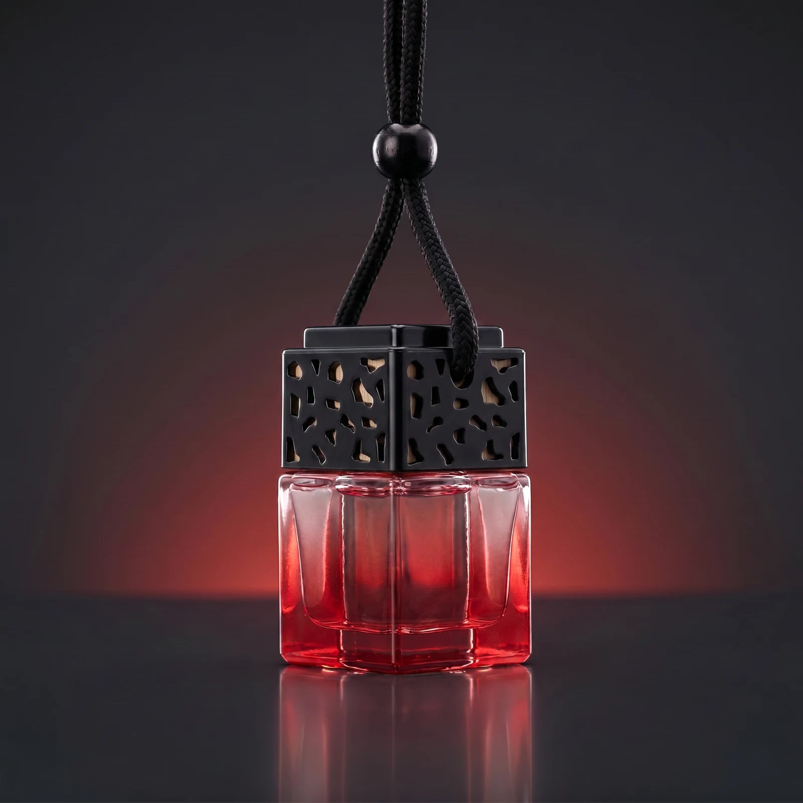 Red FRESURE car diffuser — red tinted glass cube bottle with black lattice cap on a dark studio background